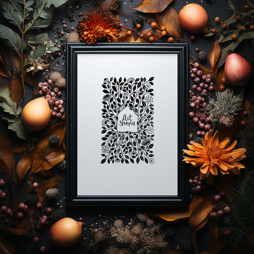 Ait Shona screen print in a black frame on a dark background surrounded by autumnal flowers and foliage