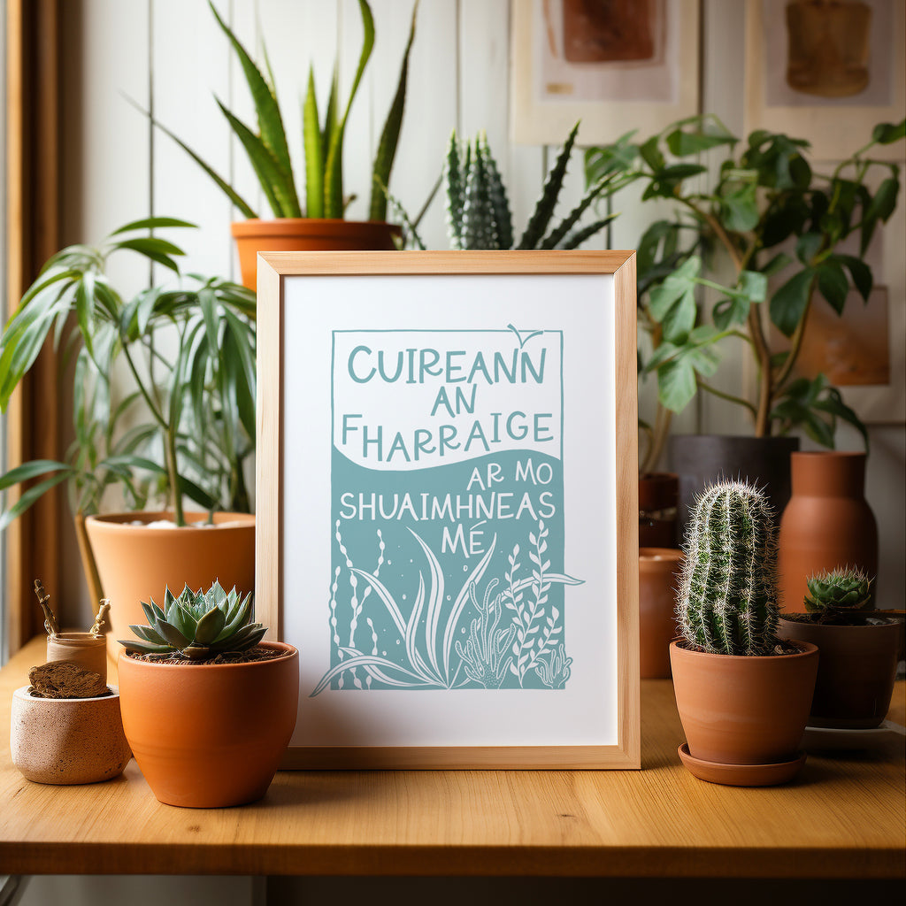 Blue and white, Irish sea screen print framed sitting on a table surrounded by cacti and plants