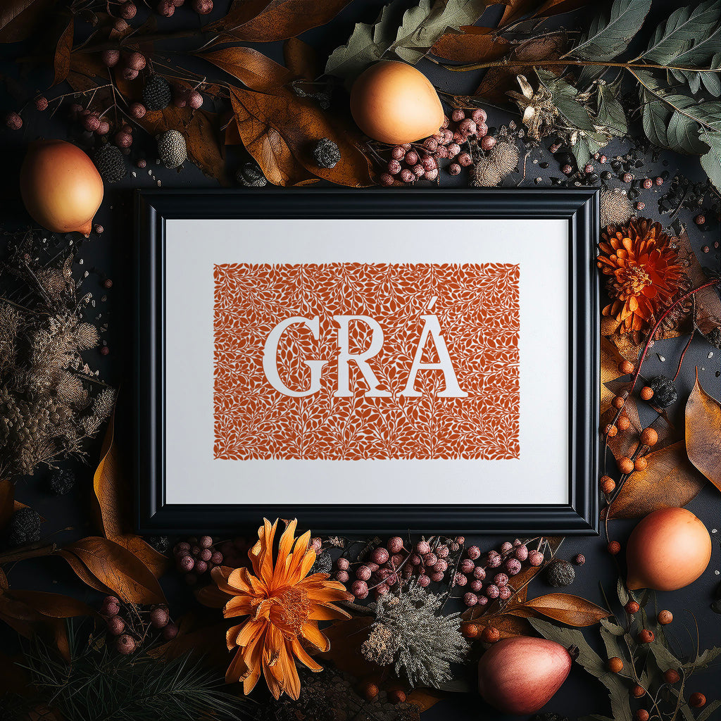 Our burnt orange Grá screen print in a black frame surrounded by Autumn foliage, flowers and fruit.