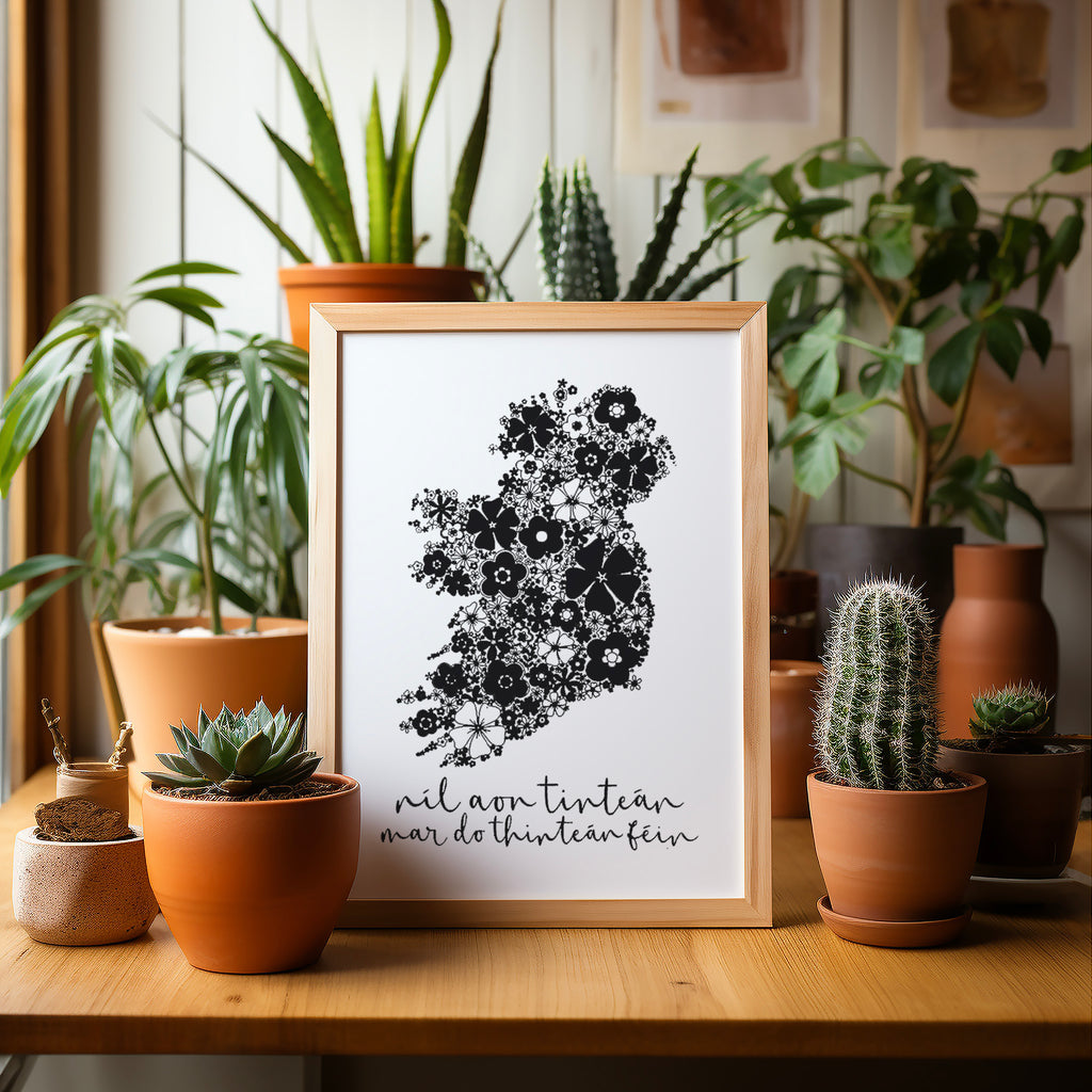 Black Irish screen print with Ireland in a wood frame on a table surrounded by potted plants and cacti