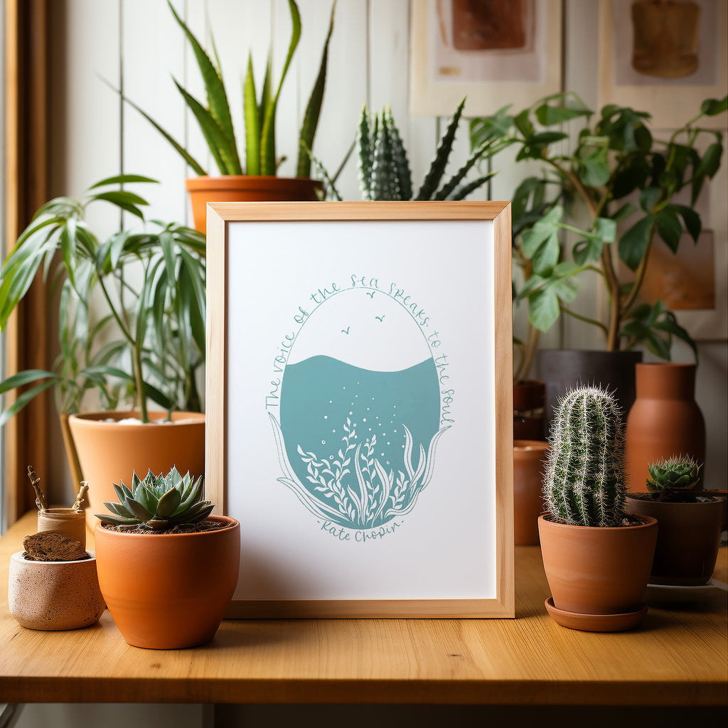 Voice of the sea... screen print in a wood frame  on a wood table surrounded by potted plants and cacti