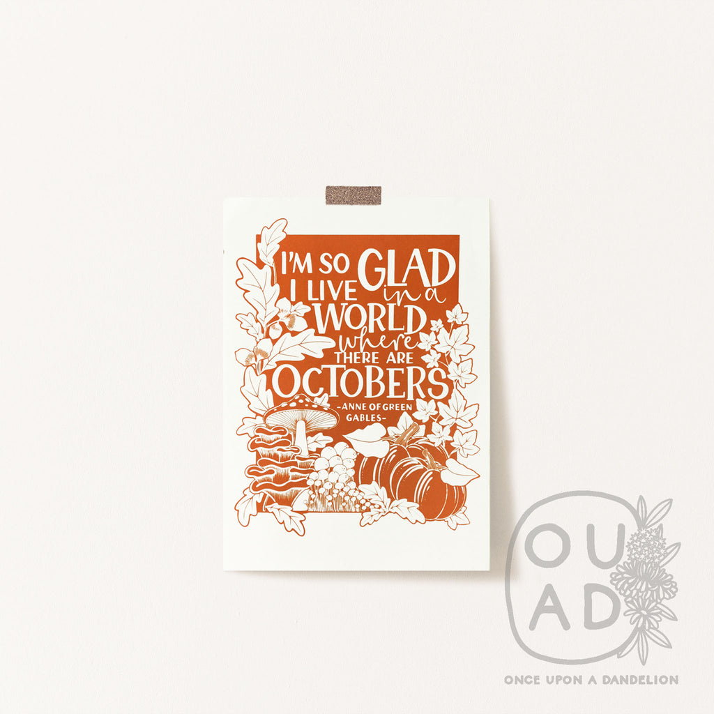 Our Anne of Green Gables screen print taped to the wall.  'I'm so glad I live in a world where there are Octobers' is printed in burnt orange paint and the design includes pumpkins, mushrooms and acorns as well as hand lettering