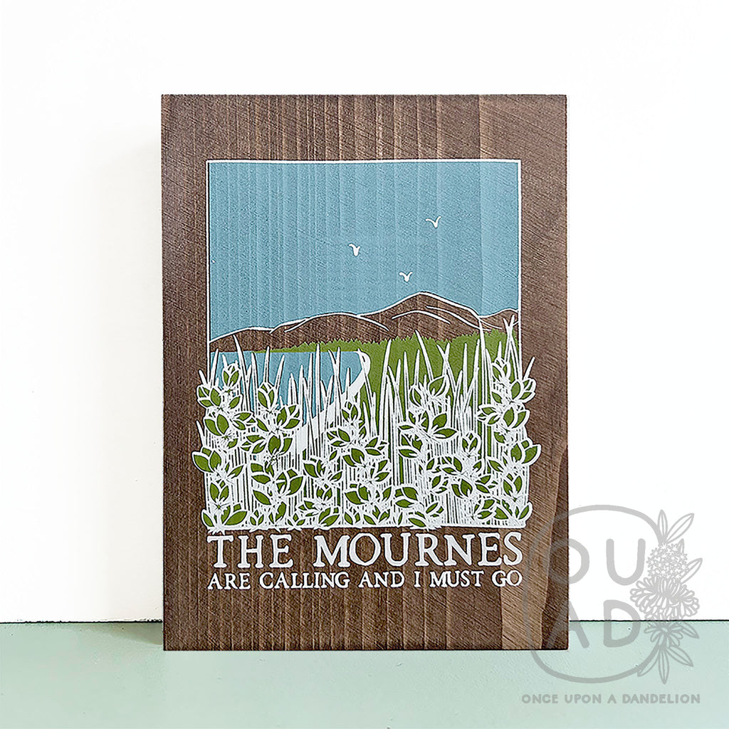 The Mournes are calling.. wood sign sitting on a green shelf against white wall