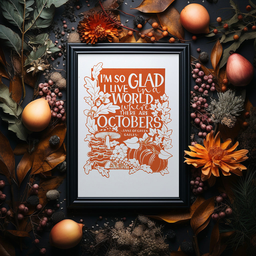 I'm so glad I live in a world where there are Octobers, a screen print of the well loved Anne of Green Gables quote.  The burnt orange colour print is in a black frame surrounded by flowers, foliage and fruit.