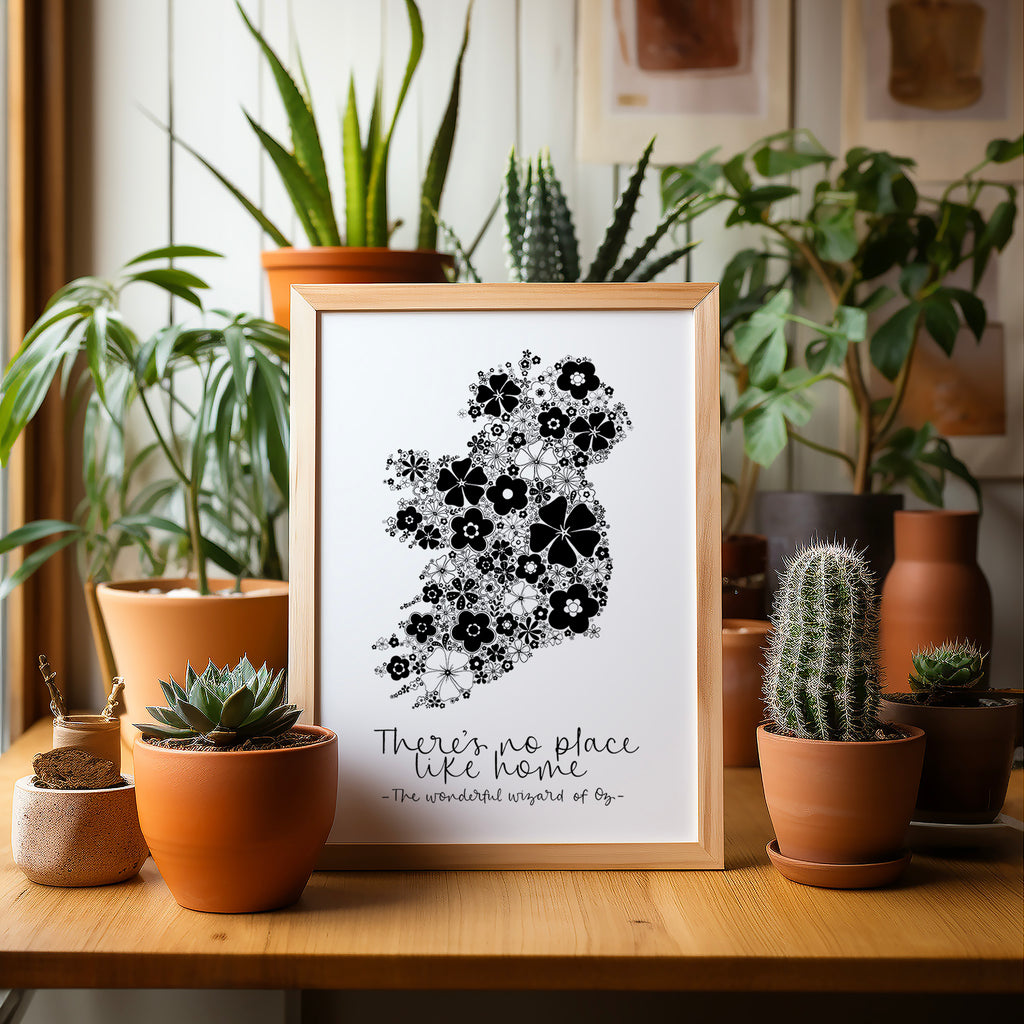 Black Ireland screen print in a wood frame sitting on a wood table surrounded by potted plants and cacti