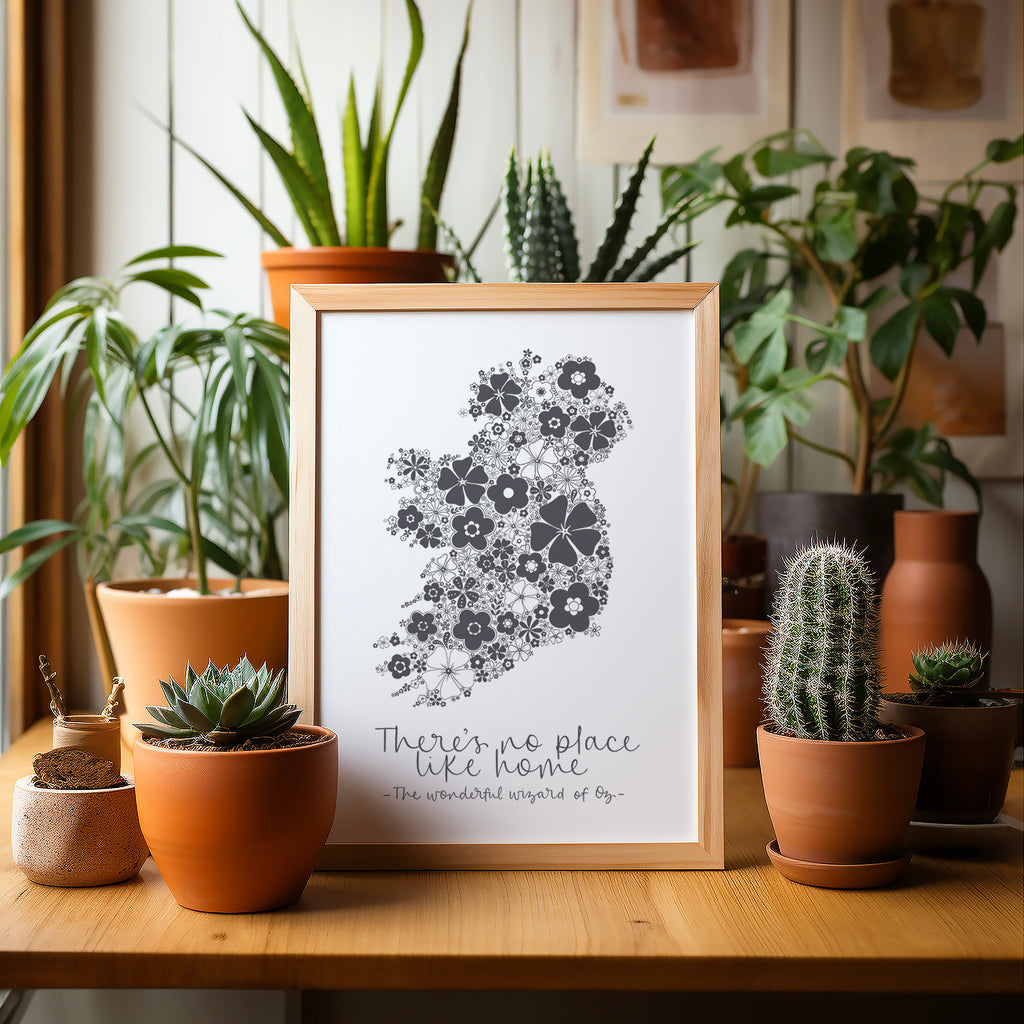 Grey Ireland screen print in a wood frame on a wood table surrounded by potted plants and cacti