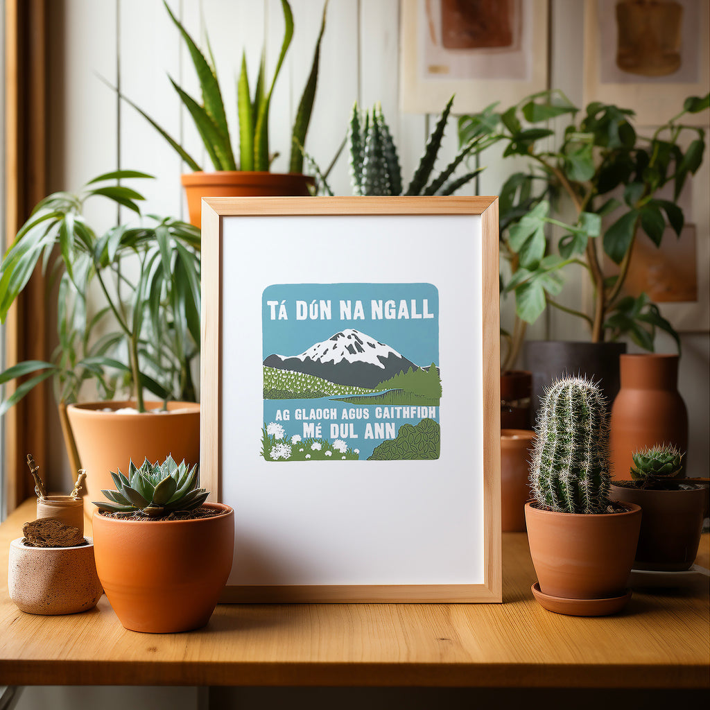 Irish Donegal screen print in a wood frame sitting on a table surrounded by potted plants and cacti