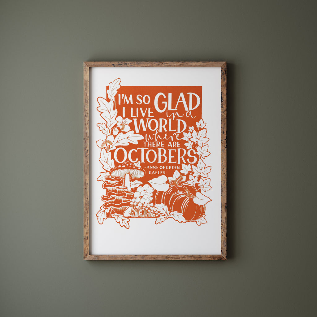 Orange Octobers screen print in a wood frame hanging on a green wall