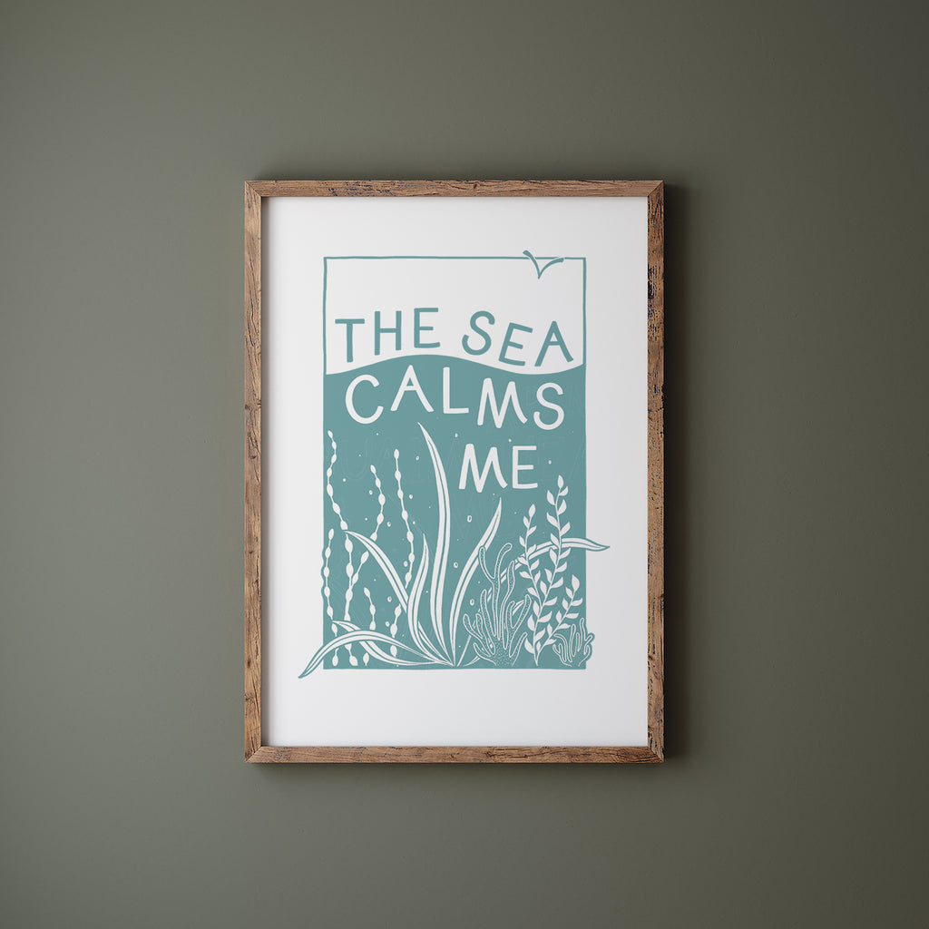 Blue and White Sea screen print in a wood frame hanging on a green wall